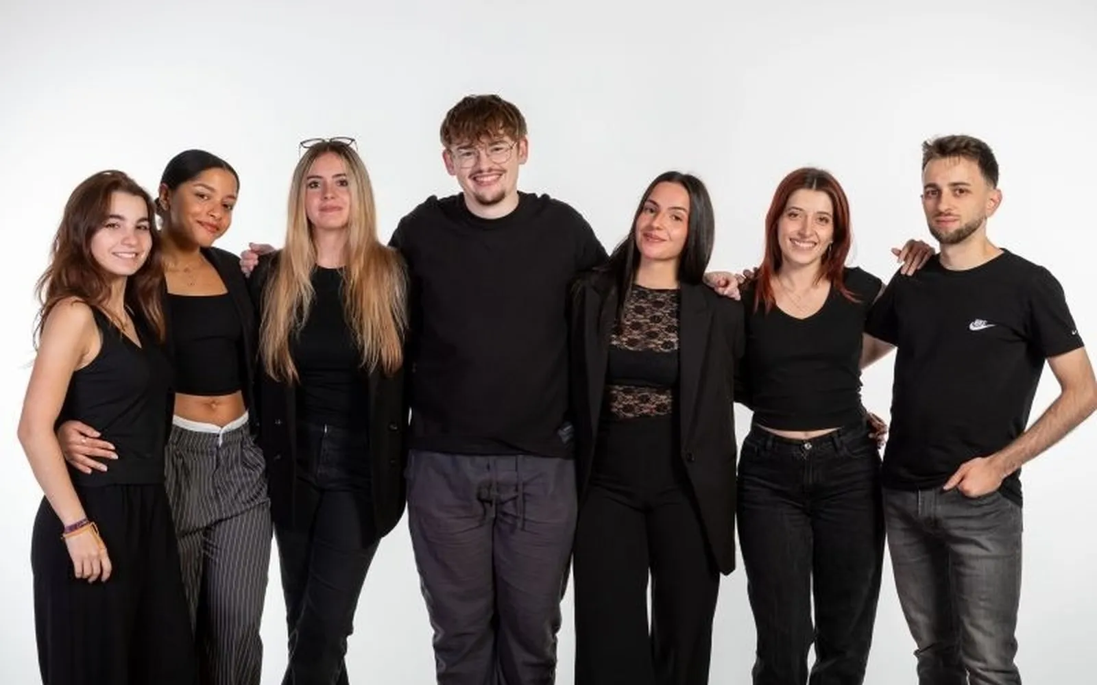 Foto de grupo del equipo del Festival Publicatessen sobre fondo blanco, con siete personas vestidas de negro.
